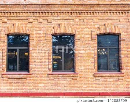 Three windows of the old mansion 19 century with brown bricks wall Three windows of the old mansion 19 century with brown bricks wall 142888799