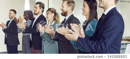 Young business people standing in a row on meeting in office clapping hands. Young business people standing in a row on meeting in office clapping hands. 142888883