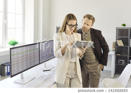 Business colleagues analyzing financial data on tablet in bright modern office Business colleagues analyzing financial data on tablet in bright modern office 142888885