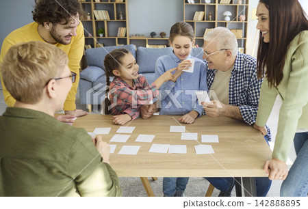 Multigenerational family playing educational card game together at home table Multigenerational family playing educational card game together at home table 142888895
