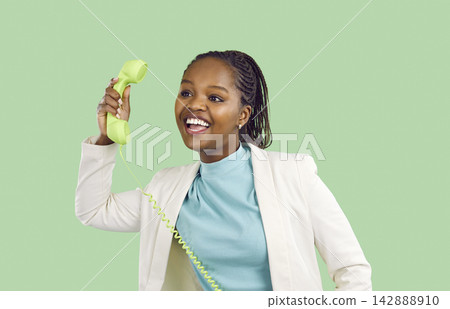 Happy young black woman on a green background chatting with her friend on the phone Happy young black woman on a green background chatting with her friend on the phone 142888910