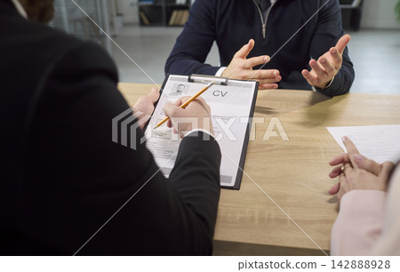 HR recruiter reviewing candidate resume during job interview in modern office HR recruiter reviewing candidate resume during job interview in modern office 142888928