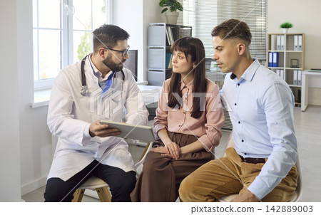 Couple consulting doctor in clinic about fertility planning and reproductive care Couple consulting doctor in clinic about fertility planning and reproductive care 142889003