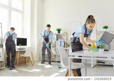 Professional cleaning team sanitizing office workspace with supplies and gloves Professional cleaning team sanitizing office workspace with supplies and gloves 142889029
