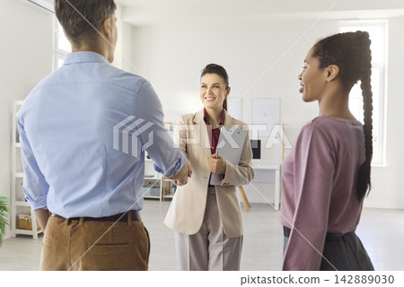 Real estate agent greeting couple with handshake at property consultation meeting Real estate agent greeting couple with handshake at property consultation meeting 142889030