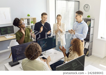 Developers team applauding coding success in modern startup office meeting Developers team applauding coding success in modern startup office meeting 142889041