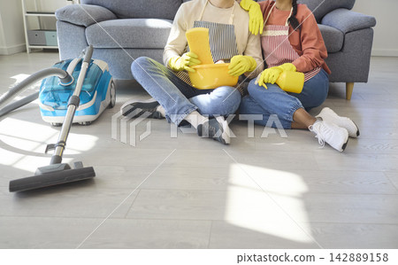 Closeup of couple cleaning living room floor with vacuum and supplies at home 142889158