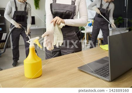 Cleaning service team preparing office workspace, janitors with gloves and tools 142889160