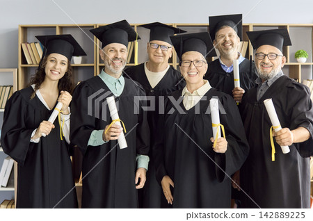 Happy adult graduates in caps and gowns celebrating with diplomas after graduation Happy adult graduates in caps and gowns celebrating with diplomas after graduation 142889225