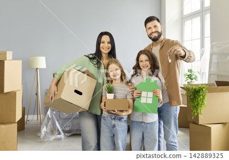 Cheerful family with boxes and keys moving into new house, celebrating together Cheerful family with boxes and keys moving into new house, celebrating together 142889325