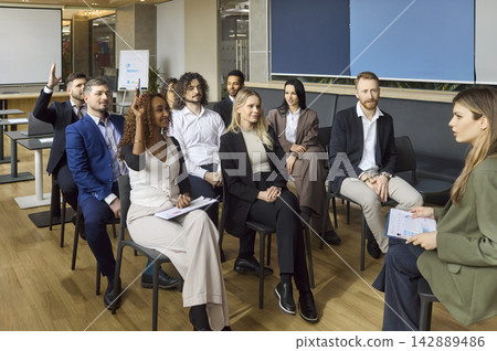 Diverse business team in office workshop raising hands during corporate training Diverse business team in office workshop raising hands during corporate training 142889486