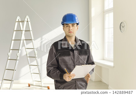 Contractor in blue hard hat with clipboard during indoor renovation inspection 142889487