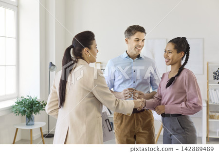 Couple meeting real estate agent, shaking hands during apartment consultation 142889489