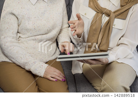 Senior woman guided by consultant using tablet for online support and planning 142889518