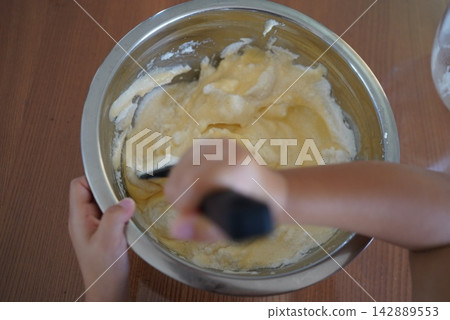 用刮刀在不銹鋼碗中攪拌酥皮麵糊。 用刮刀在不銹鋼碗中攪拌酥皮麵糊。 142889553