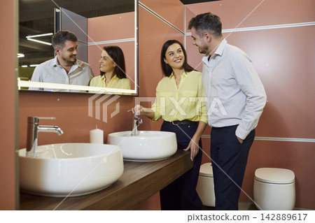 Couple customers in bathroom show room, clients choose modern sink samples, family making purchase Couple customers in bathroom show room, clients choose modern sink samples, family making purchase 142889617