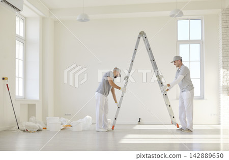 Painters team or construction workers planning repair, ladder fixing to protect during wall color Painters team or construction workers planning repair, ladder fixing to protect during wall color 142889650