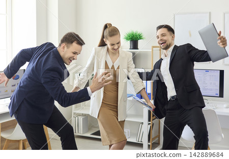 Joyful colleagues dancing in modern office after success, business team celebration Joyful colleagues dancing in modern office after success, business team celebration 142889684