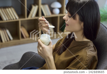 Young woman preparing to eat yogurt at home, healthy snack and relaxation concept Young woman preparing to eat yogurt at home, healthy snack and relaxation concept 142889685