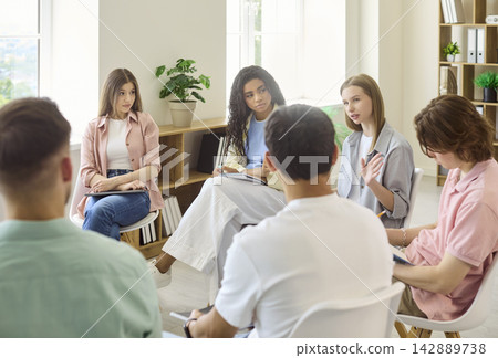 College students in circle discussing ideas at classroom meeting for teamwork 142889738
