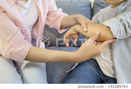 Parent applying plaster to injured child arm at home, gentle first aid care 142889763