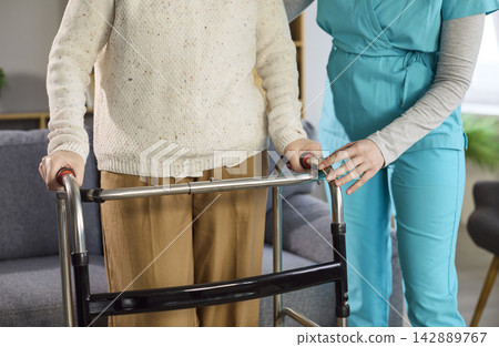 Closeup of nurse and senior hands on walker providing safe home rehabilitation 142889767