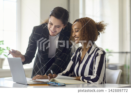 Two businesswomen collaborating at laptop in modern office, teamwork and planning Two businesswomen collaborating at laptop in modern office, teamwork and planning 142889772
