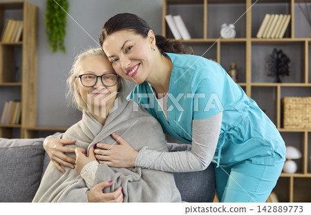 Smiling nurse hugging elderly woman at home, warm healthcare and care support Smiling nurse hugging elderly woman at home, warm healthcare and care support 142889773