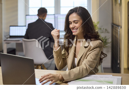 Joyful businesswoman celebrating sales success at laptop in bright modern office Joyful businesswoman celebrating sales success at laptop in bright modern office 142889830