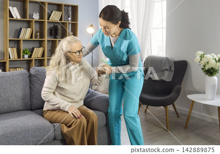 Home healthcare nurse assisting senior woman to stand up with gentle support Home healthcare nurse assisting senior woman to stand up with gentle support 142889875