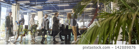 Diverse business team networking before meeting in modern glass walled office Diverse business team networking before meeting in modern glass walled office 142889876