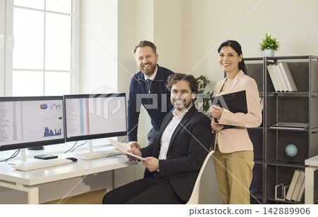 Smiling business team of three colleagues in modern office with analytics Smiling business team of three colleagues in modern office with analytics 142889906