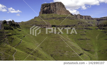 Rocky mountain landscape above green rolling hills under a clear blue sky Rocky mountain landscape above green rolling hills under a clear blue sky 142890107