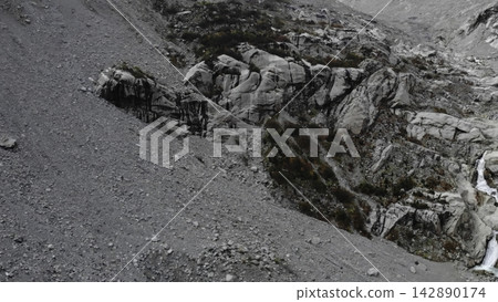 Rugged rocky mountain slope with scree and snow in cold daylight . Media Rugged rocky mountain slope with scree and snow in cold daylight . Media 142890174