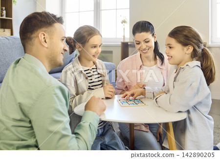 Smiling family playing board game at home, parents and kids enjoying quality time Smiling family playing board game at home, parents and kids enjoying quality time 142890205