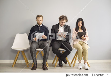 Applicants seated for recruitment interview filling forms while awaiting hiring 142890396