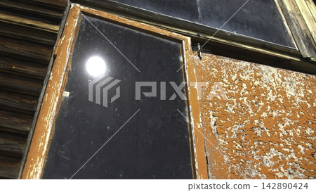 Weathered orange window frame with peeling paint and dark reflective glass Weathered orange window frame with peeling paint and dark reflective glass 142890424
