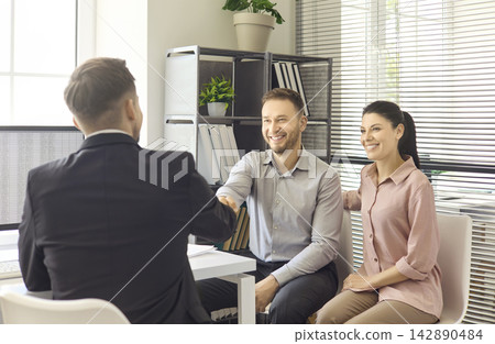Couple shakes hands with realtor in office after successful property consultation Couple shakes hands with realtor in office after successful property consultation 142890484
