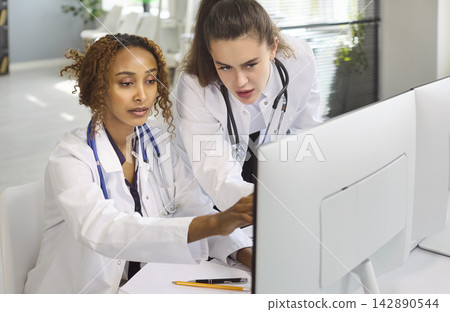 Doctors collaborating at desktop to review records and discuss diagnosis in clinic Doctors collaborating at desktop to review records and discuss diagnosis in clinic 142890544