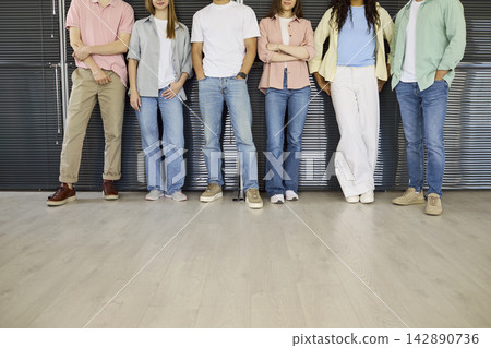 Diverse students group standing on campus in jeans and sneakers, cropped view Diverse students group standing on campus in jeans and sneakers, cropped view 142890736
