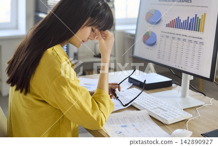 Overworked businesswoman with headache at office desk, eye strain from computer 142890927