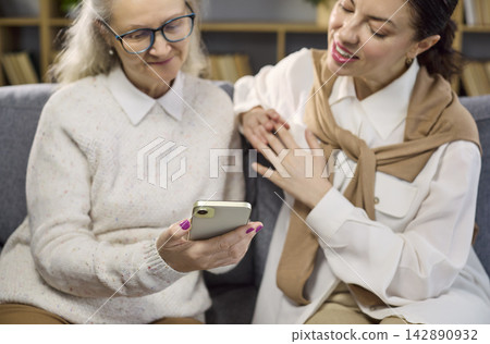 Daughter guides elderly mother using smartphone for online services and tasks Daughter guides elderly mother using smartphone for online services and tasks 142890932