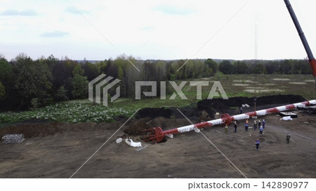 Aerial crane lifting a long structure at a rural construction site Aerial crane lifting a long structure at a rural construction site 142890977