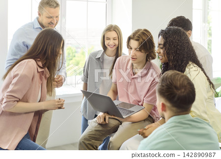 Teacher guides students in laptop group project discussion in bright classroom 142890987