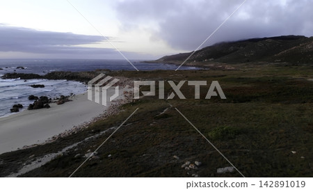 Rugged coastal shoreline with rocky beach and cloudy sky Rugged coastal shoreline with rocky beach and cloudy sky 142891019
