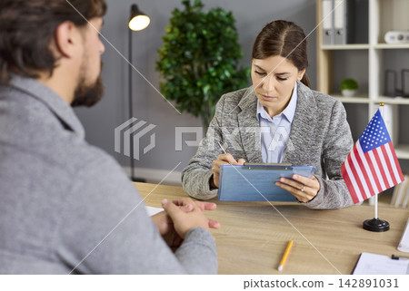 Consular interview process of US visa lawyer and applicant in embassy with flag Consular interview process of US visa lawyer and applicant in embassy with flag 142891031