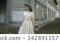 Woman in Light Dress Standing by Old Wooden House 142891157