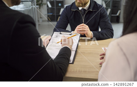 Employer and HR recruiter evaluating CV and application at hiring interview table Employer and HR recruiter evaluating CV and application at hiring interview table 142891267