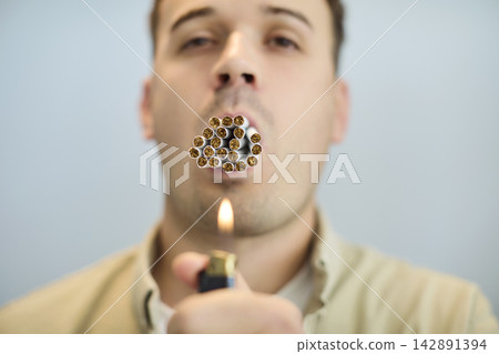 Man lighting multiple cigarettes at once, symbolizing addiction and health risk Man lighting multiple cigarettes at once, symbolizing addiction and health risk 142891394