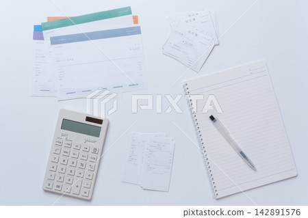 A desk image for tax return and accounting work, with receipts, invoices, and a calculator. A desk image for tax return and accounting work, with receipts, invoices, and a calculator. 142891576